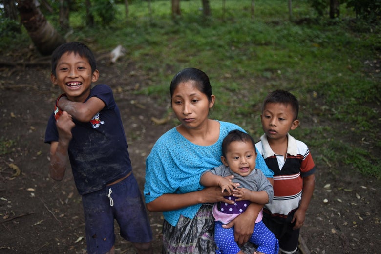 Claudia Maquin holds her 6-month-old daughter Angela, with her children Abdel and Elvis standing beside her.
